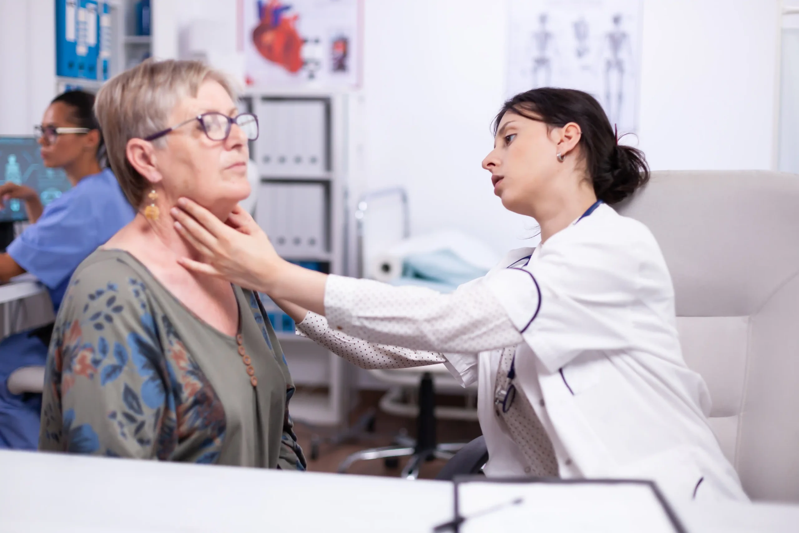 young medic palpating neck senior woman elderly patient visiting doctor hospital checking thyroid throat touching health clinic healthcare specialist medicare treatment medical concept 11zon